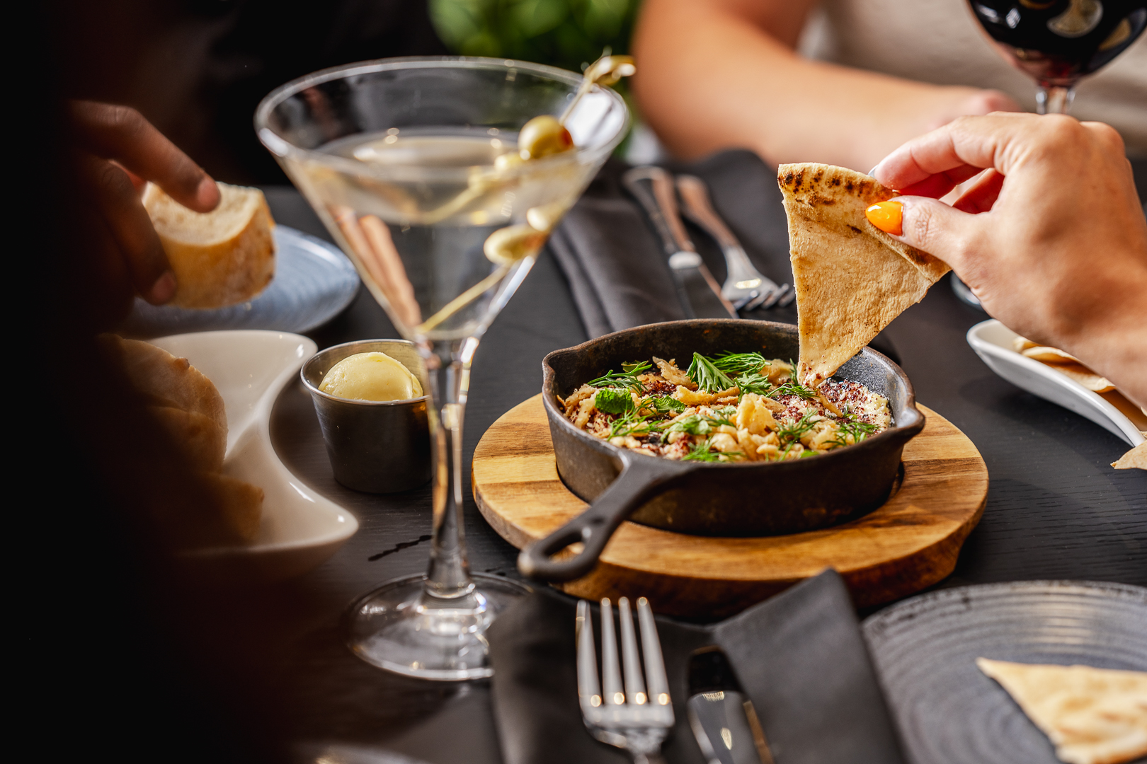 A guest dipping a pita wedge into hummus